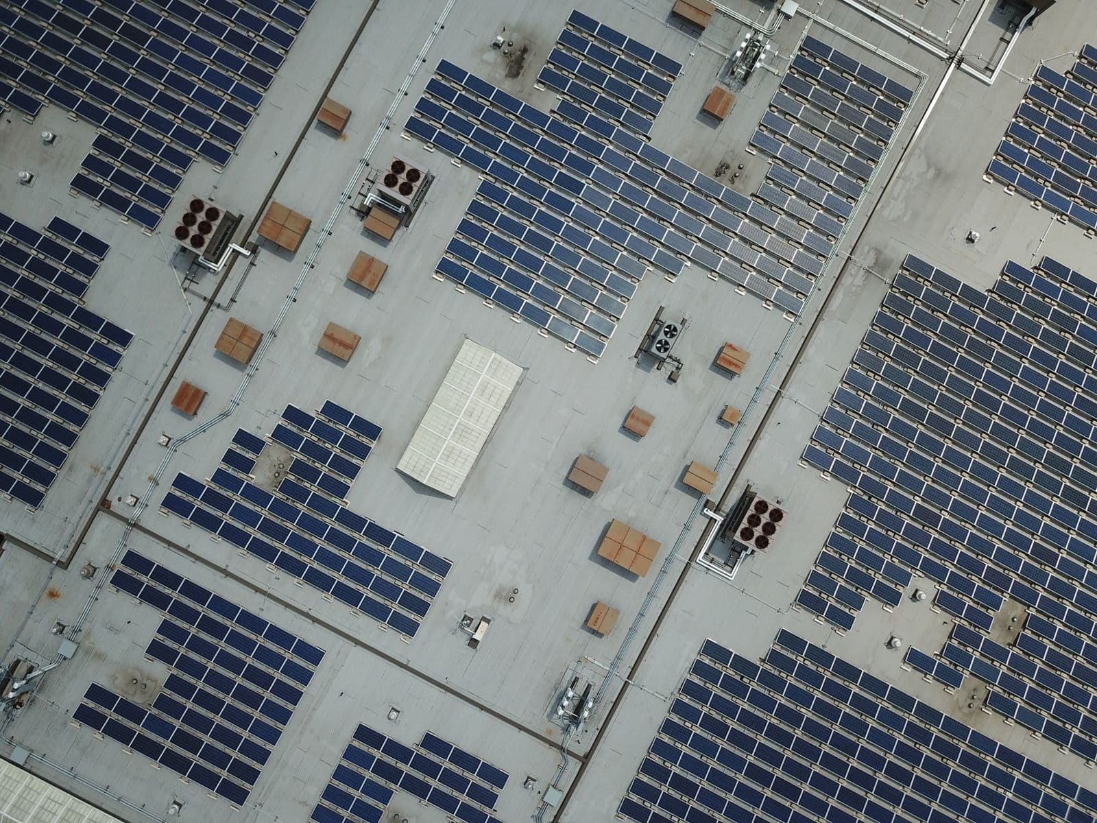 Luchtfoto van een groot plat dak vol zonnepanelen op een bedrijfshal