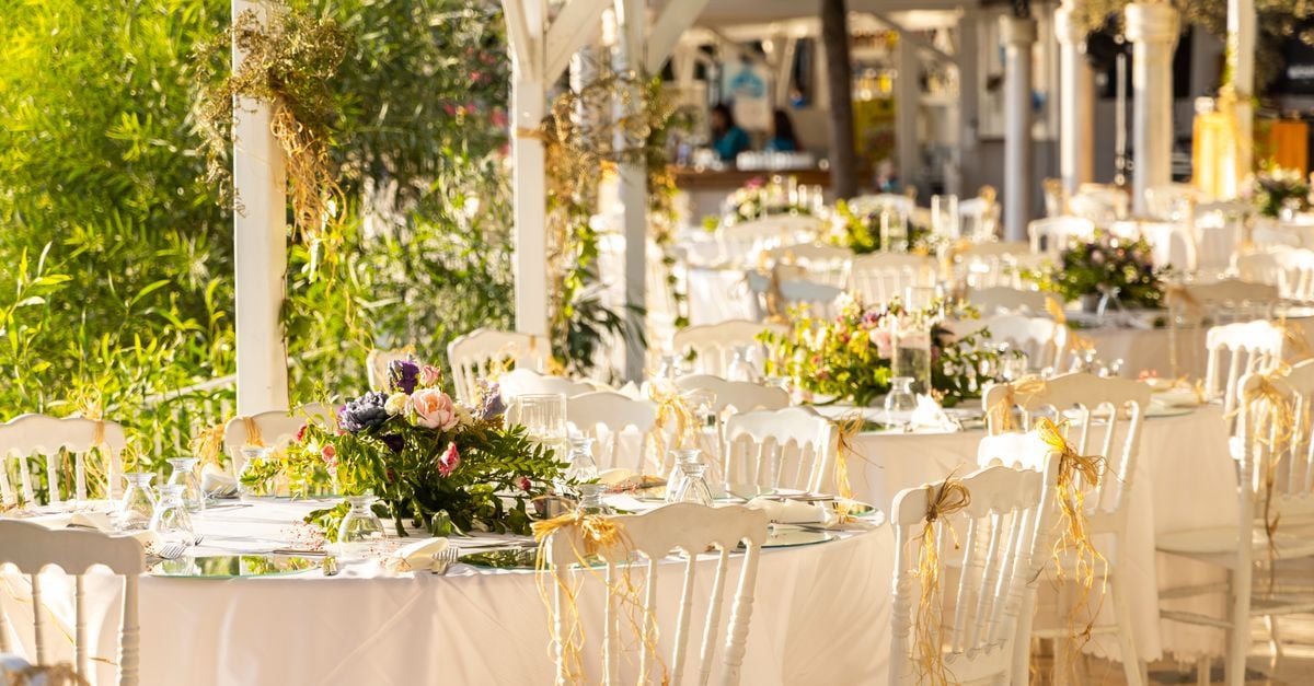 Beautifully arranged outdoor wedding reception with floral centerpieces and white decor.