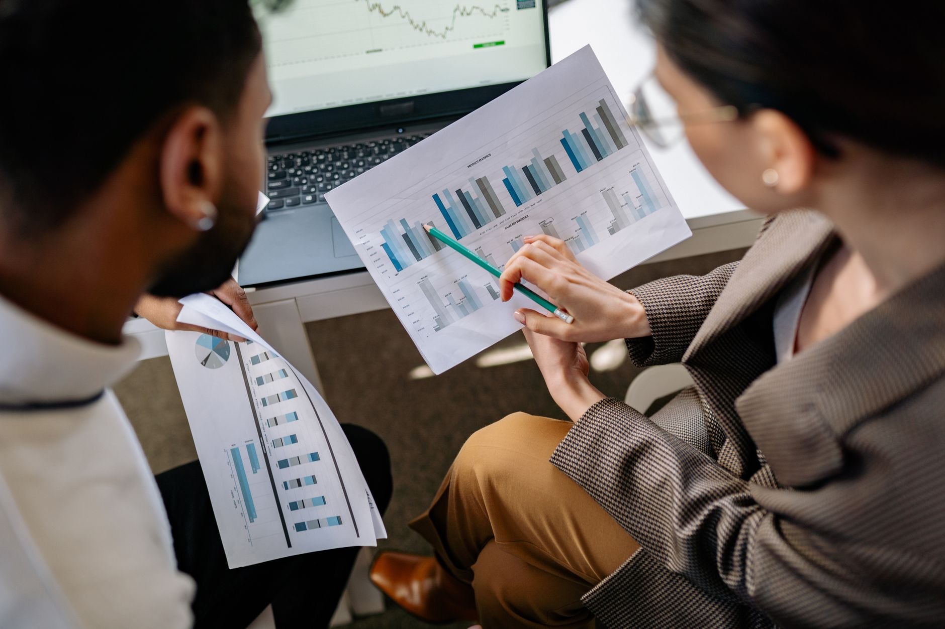 Collega's werken samen aan datagraphieken en bespreken bedrijfsstrategieën in een kantooromgeving.