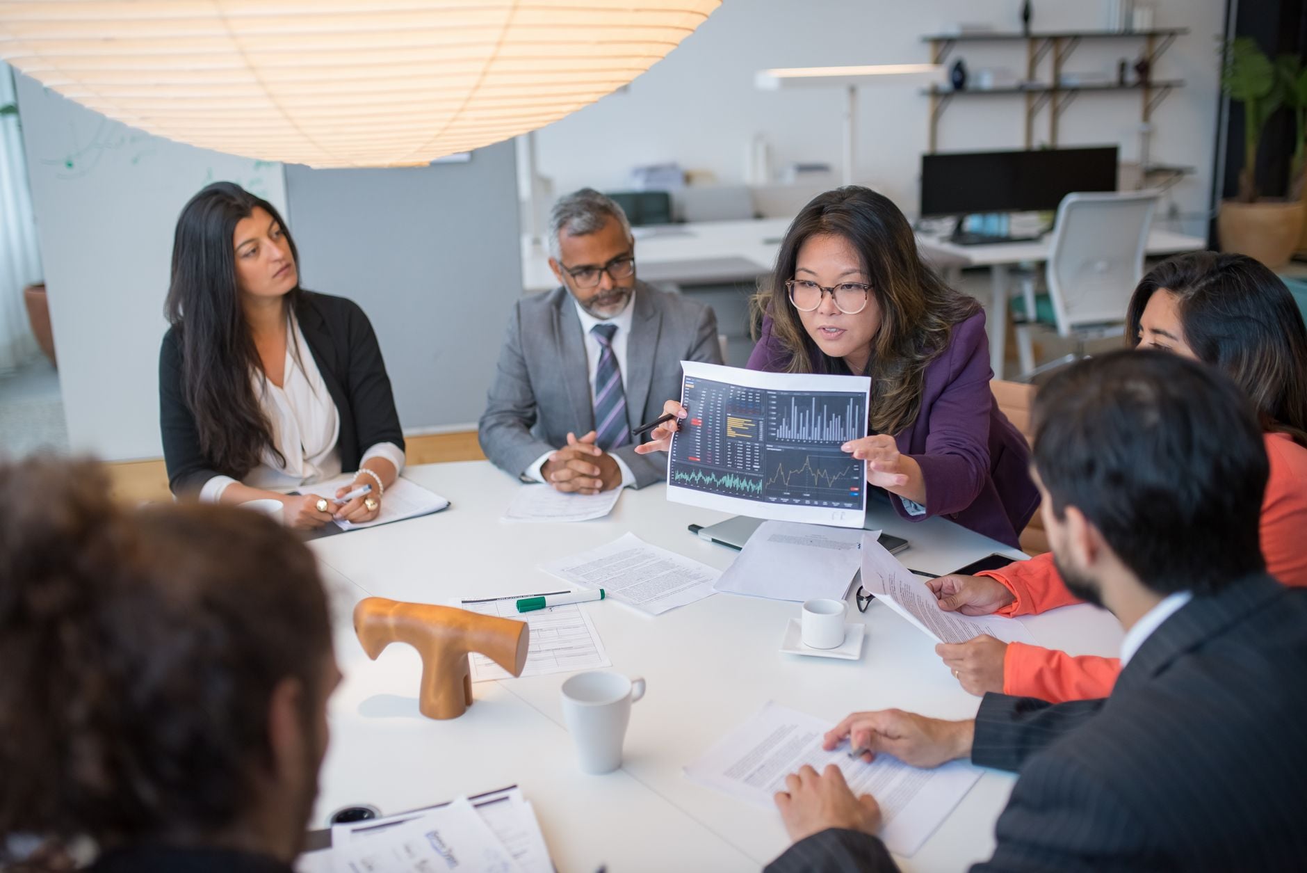 Multicultureel team bespreekt analytics in een professionele zakelijke vergaderomgeving met datadiagrammen.