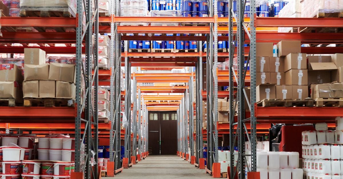 Wide angle view of a warehouse with stocked shelves and boxes.