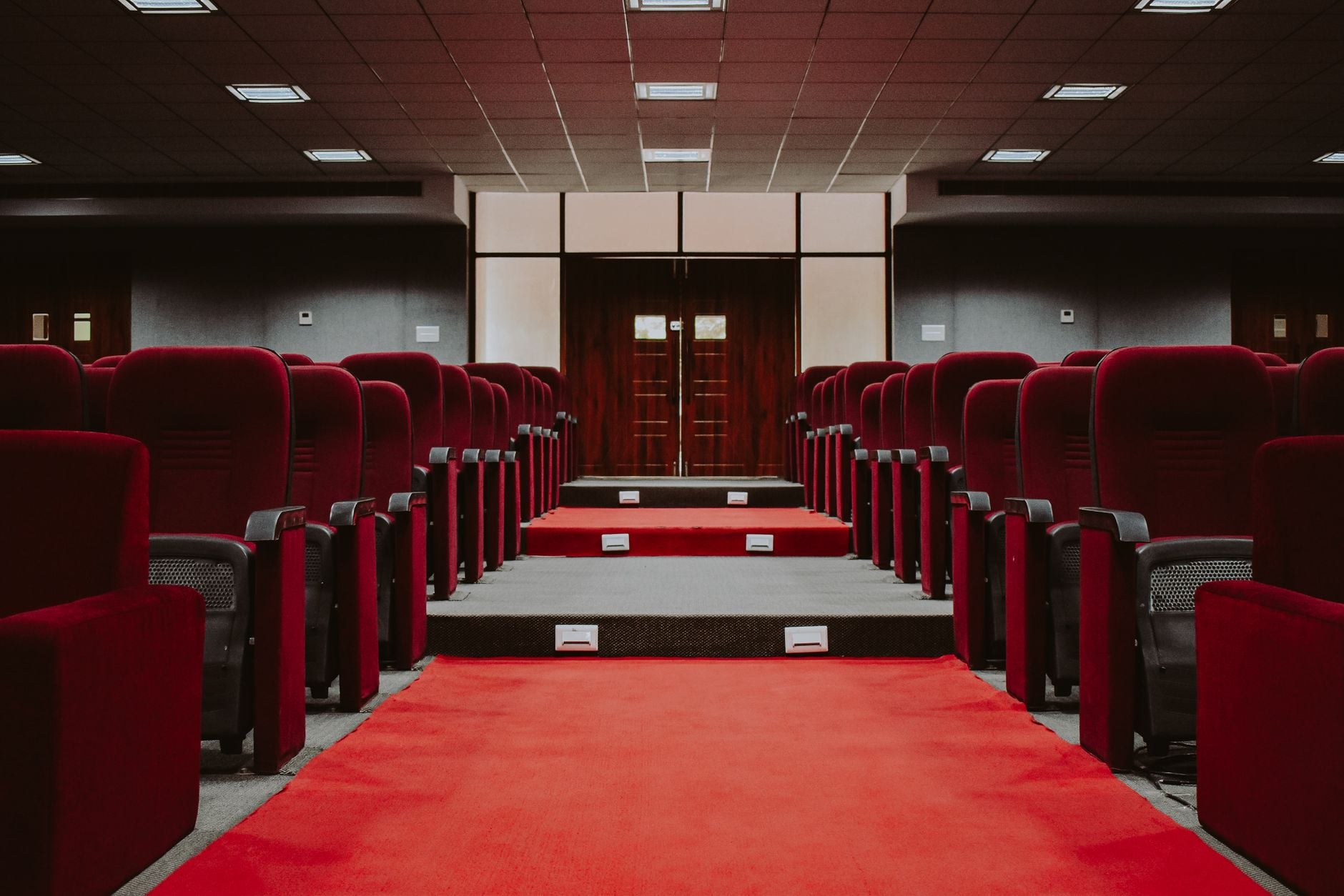 Een luxueus leeg auditorium met rijen rode fluwelen stoelen en een rode loper.
