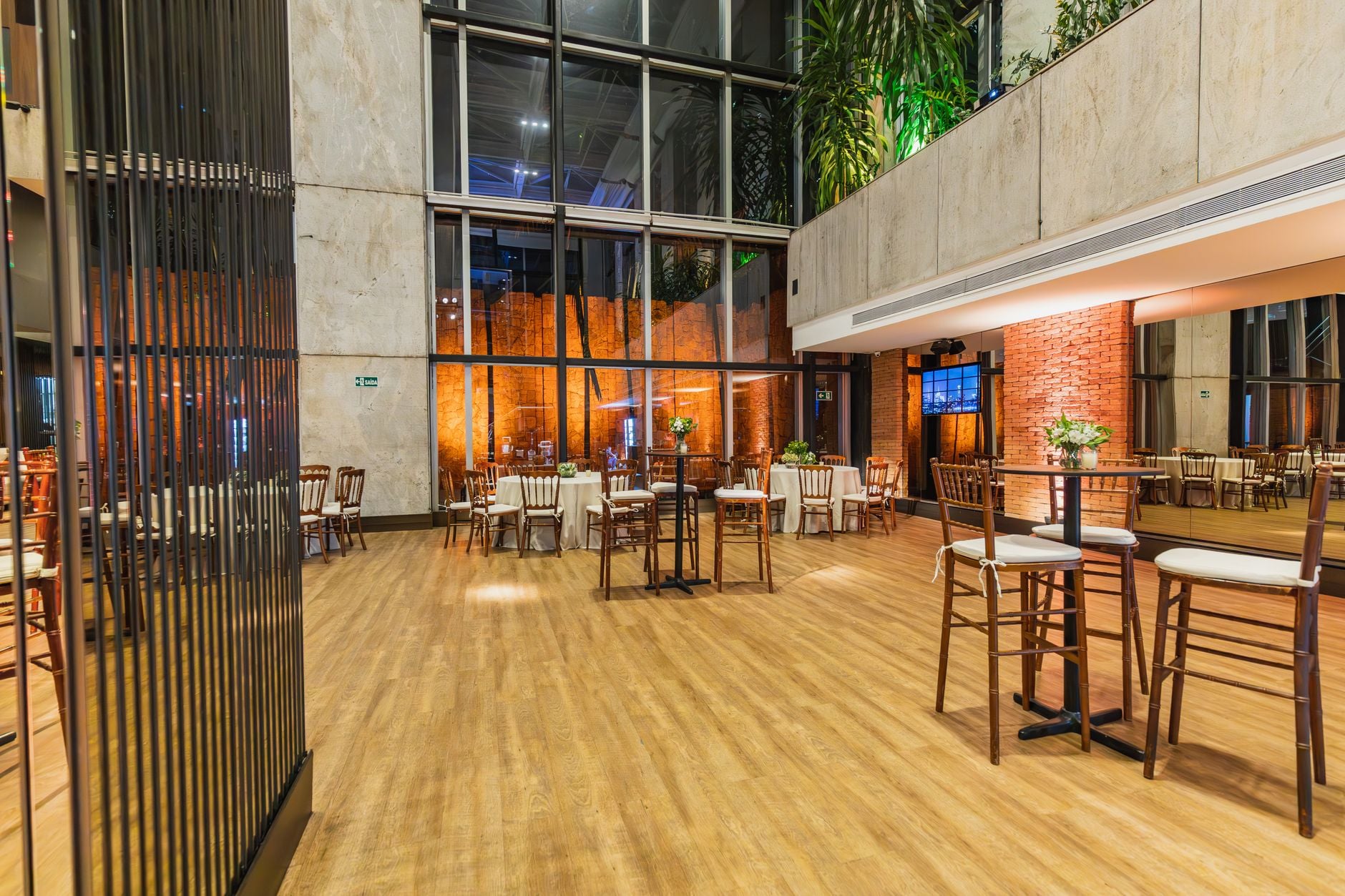 Een ruime feestzaal elegant ingericht voor een formele gelegenheid met houten stoelen en grote ramen.