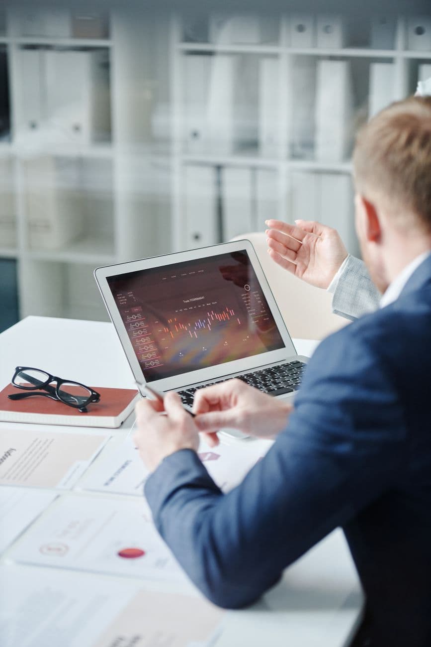 Twee professionals die een financiële analyse bespreken op een laptop in een modern kantoor.