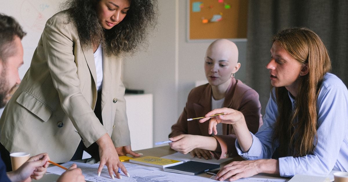 Group of concentrated coworkers working together at table on business strategy with documents during briefing in conference room in office