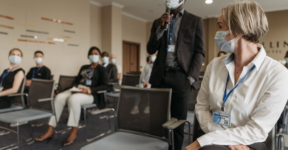 Diverse group of professionals in a business meeting wearing masks for safety.