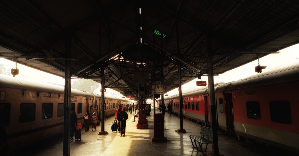 Travelers and trains at Lucknow Railway Station captured in warm daylight.