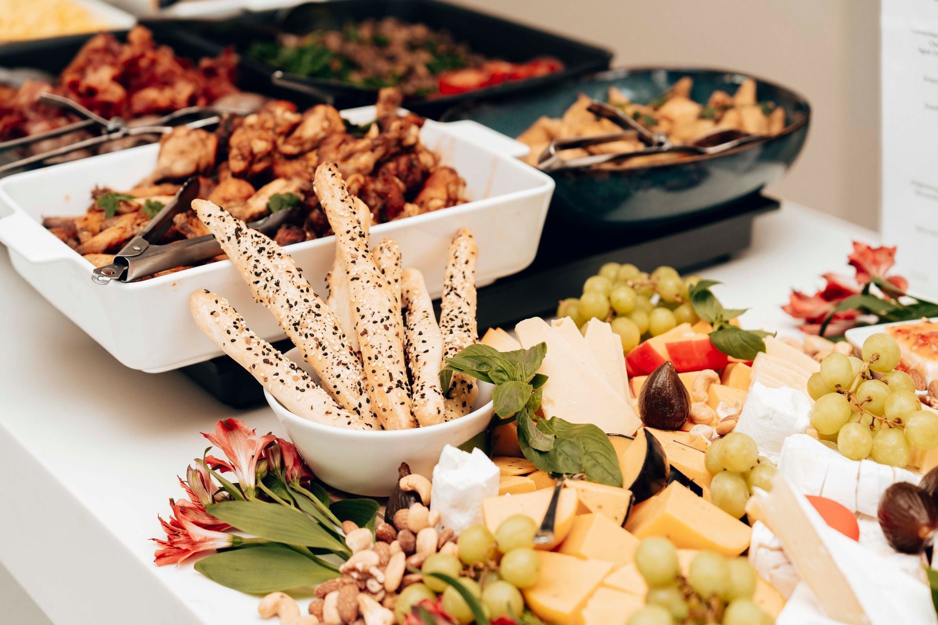Een smakelijke assortie van kazen, broodsticks en fruit in een buffetsetting. Perfect voor catering evenementen.