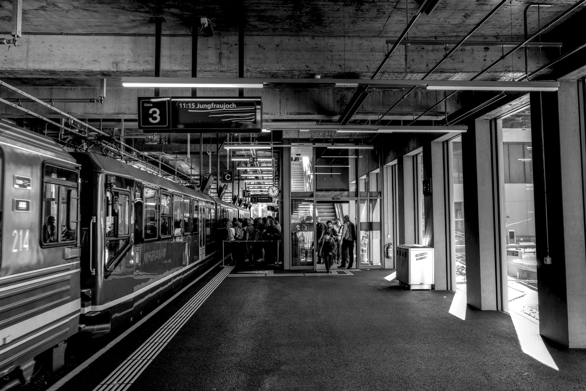 Een sfeervolle zwart-witfoto van een treinstation op Jungfraujoch, met een trein en passagiers.