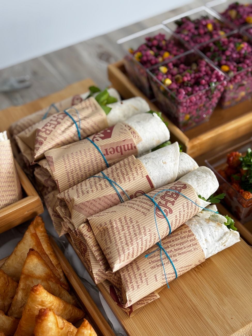 Verschillende soorten verpakte sandwiches en kleurrijke salades geserveerd op bamboe dienbladen.