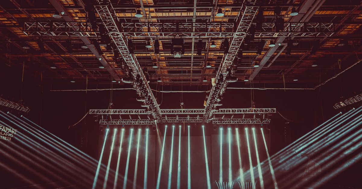 A contemporary indoor stage setup featuring dramatic lighting and intricate architectural patterns.