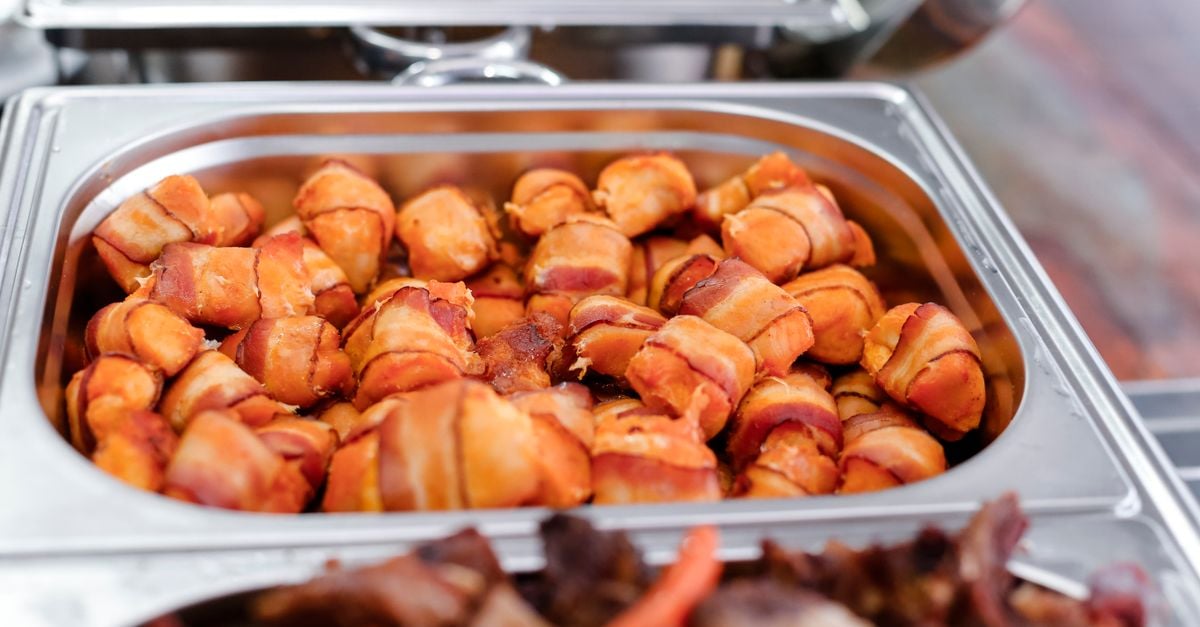 Delicious bacon wrapped appetizers ready to serve in a catering tray. Perfect for events.