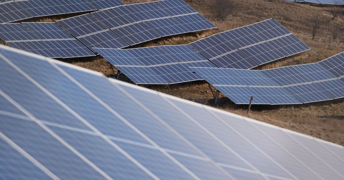 Aerial view of a large solar panel farm capturing sunlight in an open field.
