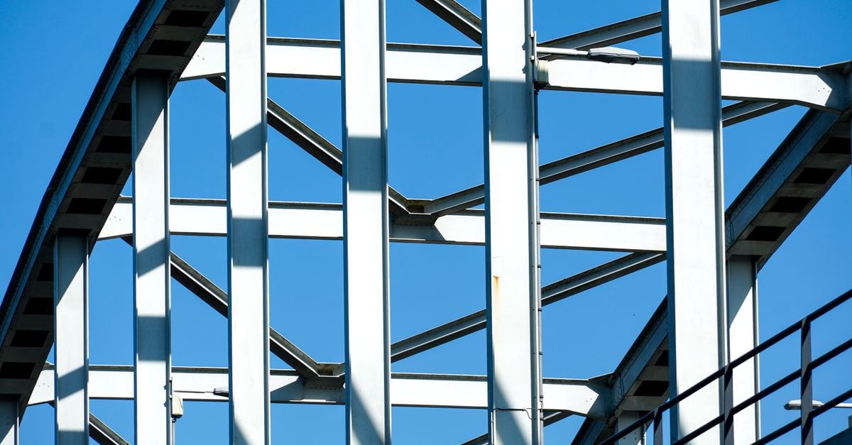 Close-up van het geometrische framewerk van een stalen brug tegen een helderblauwe lucht. Hier ziet u de moderne architectuur.