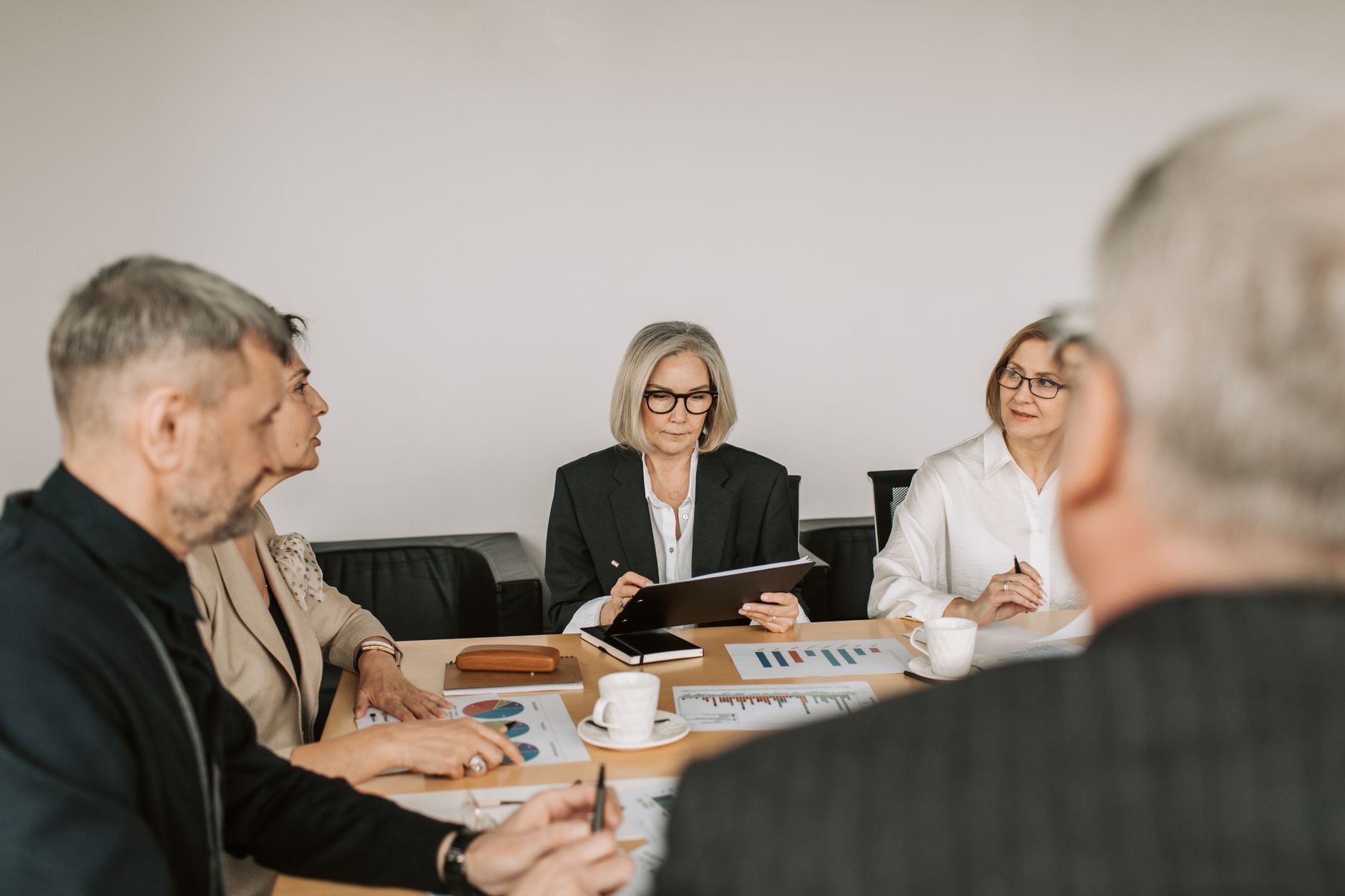 Senior professionals betrokken bij een gezamenlijke zakelijke vergadering in een moderne kantooromgeving.