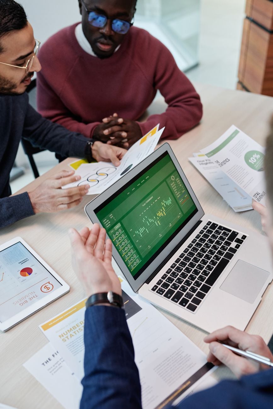 Een multicultureel team dat betrokken is bij een samenwerkende vergadering met een laptop en documenten in een moderne kantooromgeving.