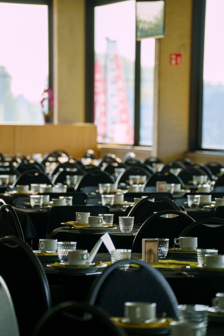Rijen keurig gerangschikte tafels en stoelen in een lichte restaurantomgeving, met koffiekopjes klaar voor de gasten.