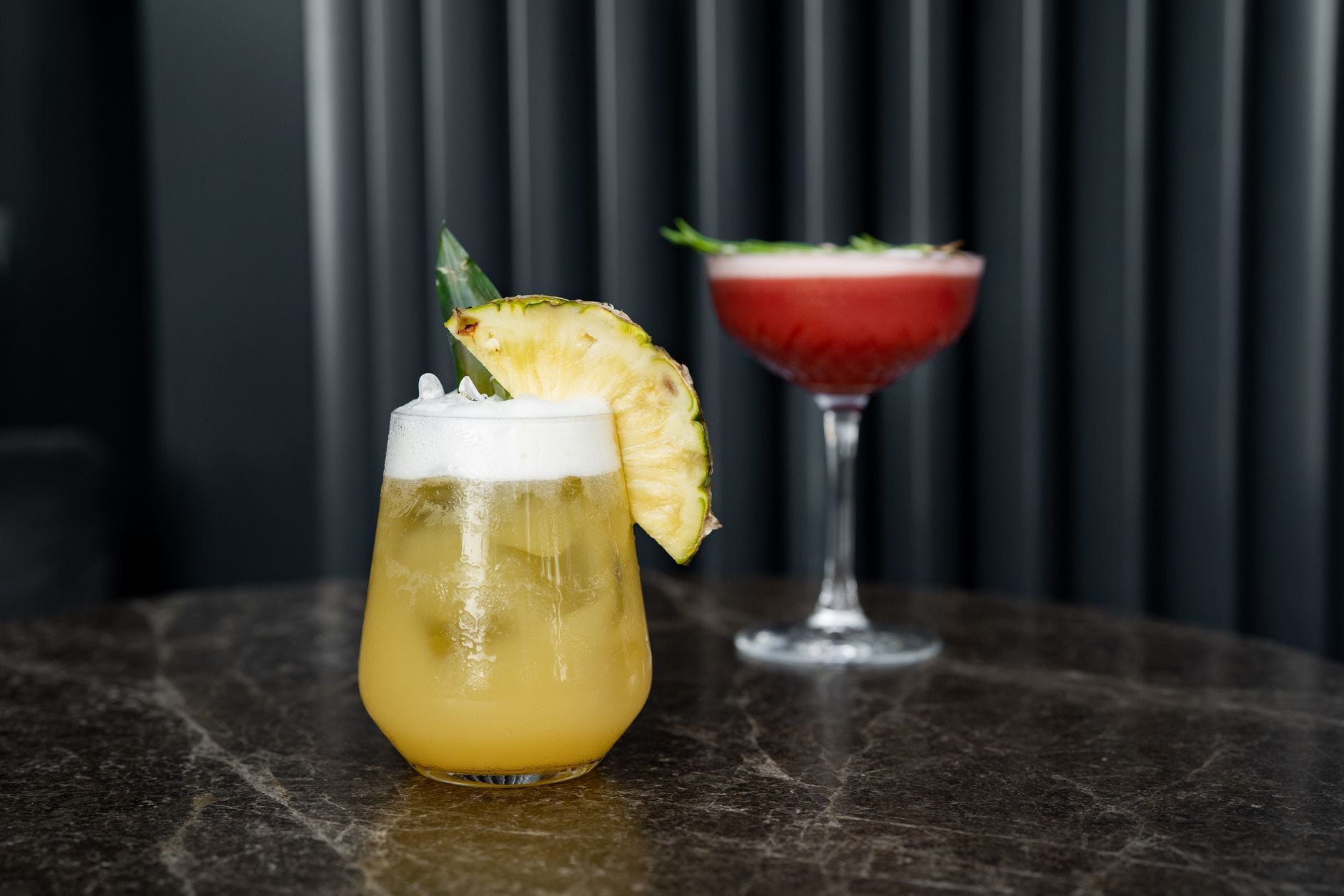 Close-up of colorful cocktails with pineapple garnishes on a marble table. Perfect for summer or tropical themed settings.