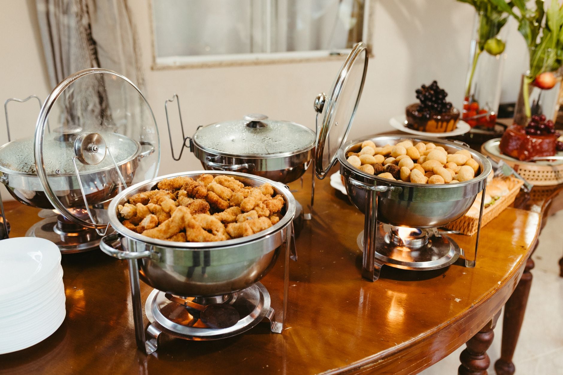 Een heerlijk buffet met diverse hapjes in warmhoudschalen op een houten tafel.
