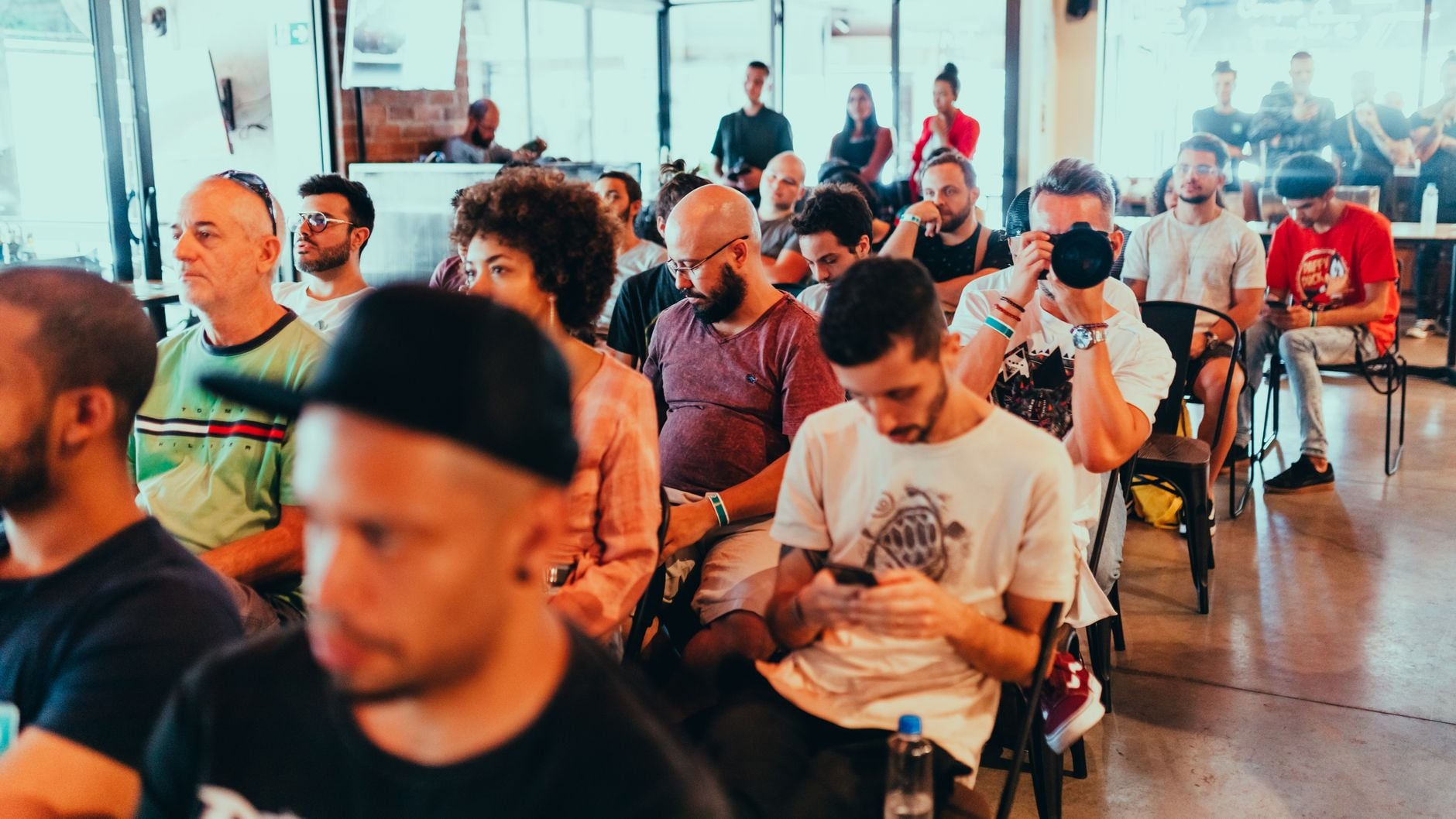 Diverse groep mensen die een moderne conferentie bijwonen, gericht op luisteren en discussies.