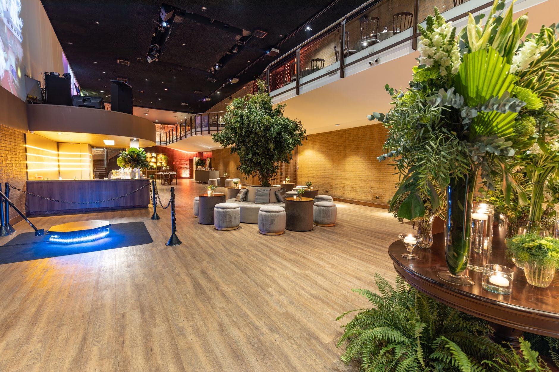 Ruime hotel-lounge met moderne meubels, planten en een stijlvolle bar, perfect voor evenementen of ontspanning.