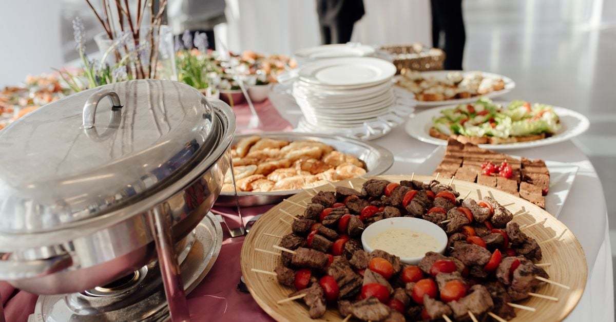 Tasty grilled meat with tomatoes served on table with abundance of delicious dishes and dishware during banquet in modern restaurant