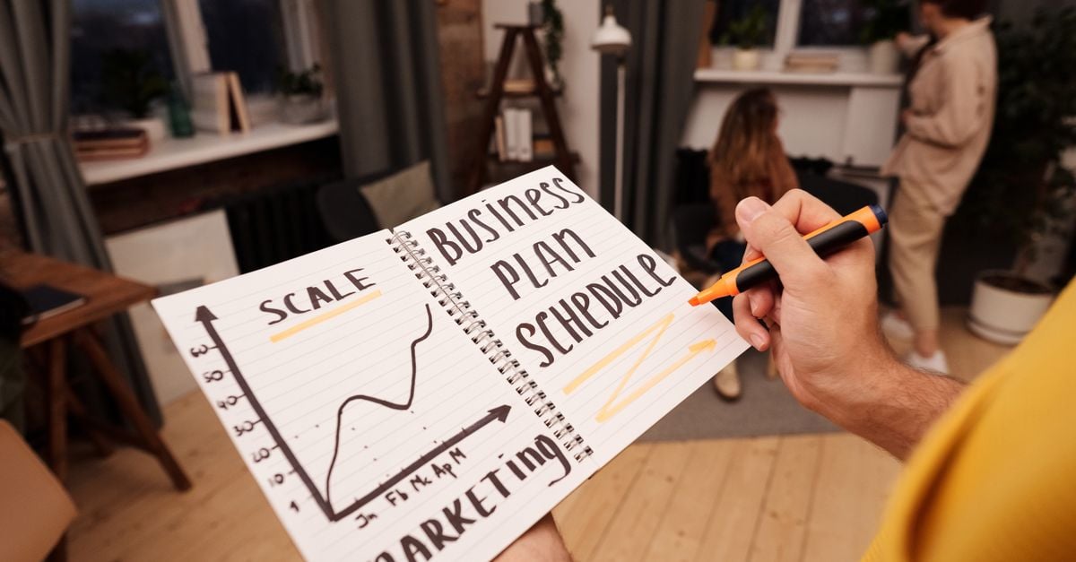 Person holding a notebook with planning details and graph for business strategy indoors.