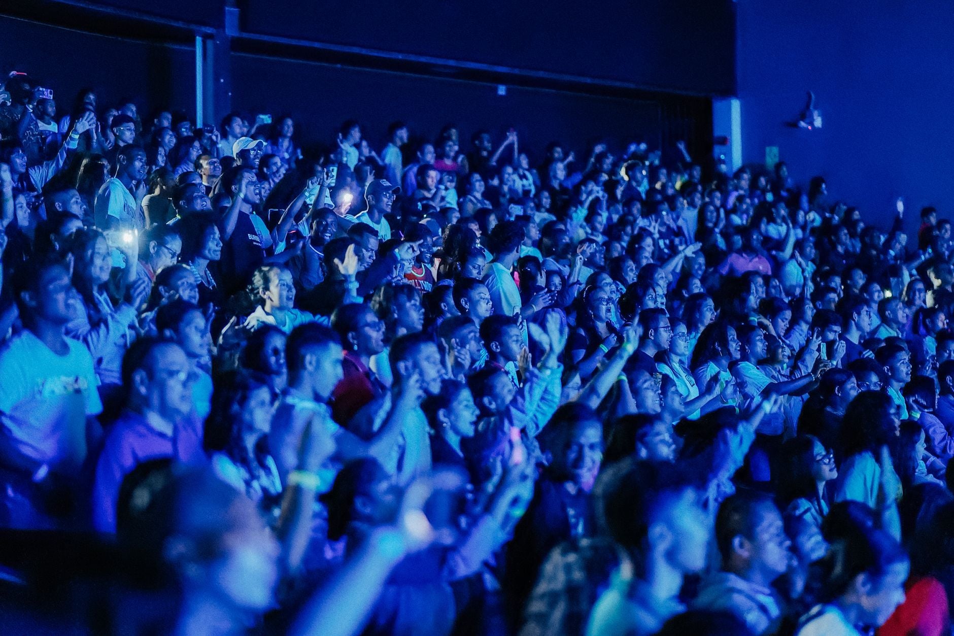 Een volle menigte geniet van een live concert, ondergedompeld in dynamisch blauw licht, dat de opwinding vastlegde.