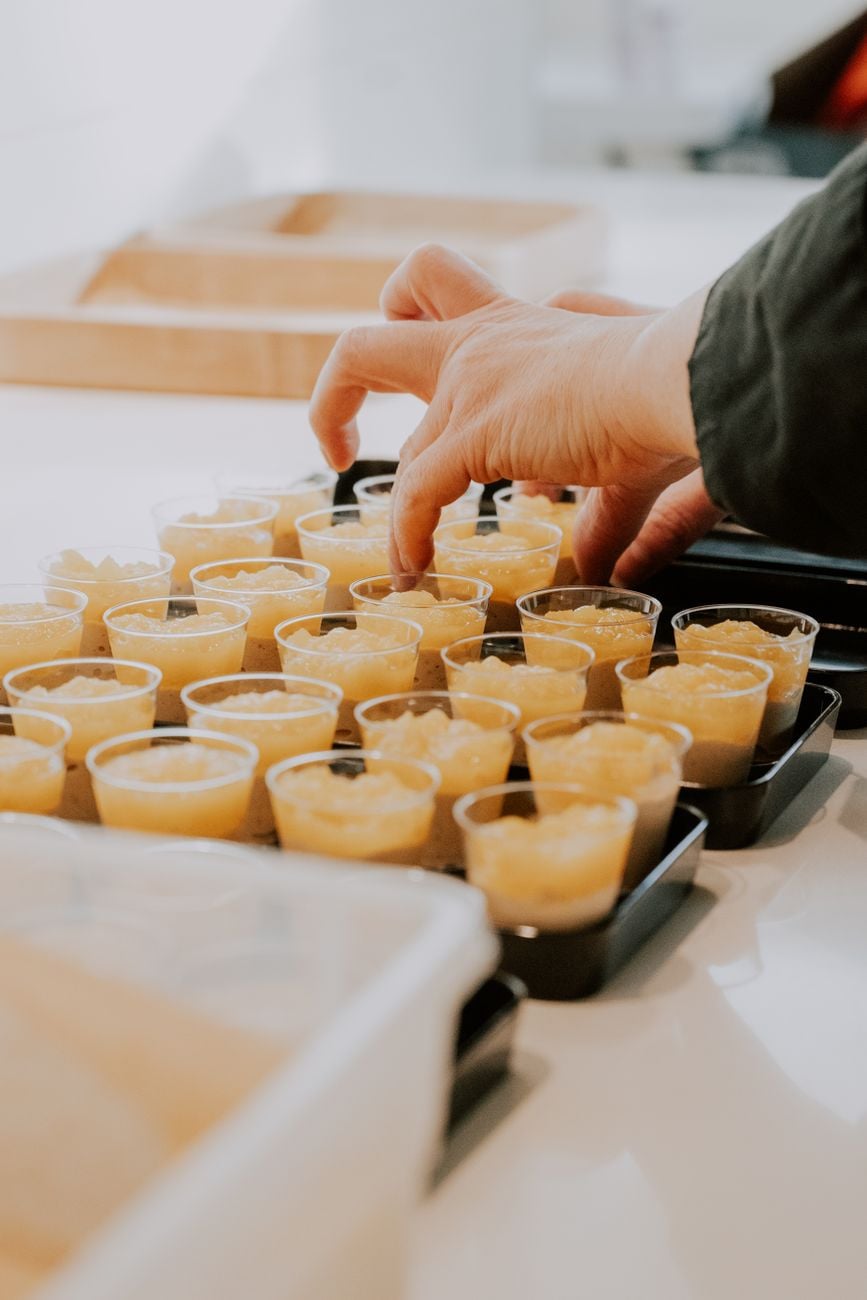Hand die kleine dessertshots op een dienblad rangschikt, perfect voor catering en evenementen.