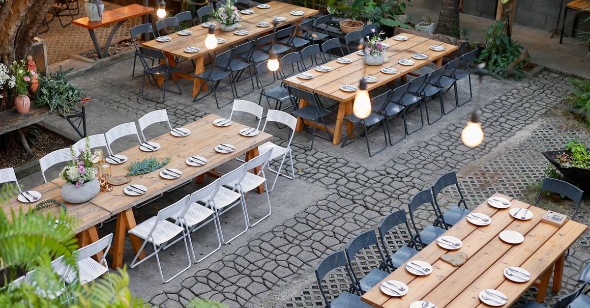 Scenic outdoor venue setup with rustic tables and floral decorations.