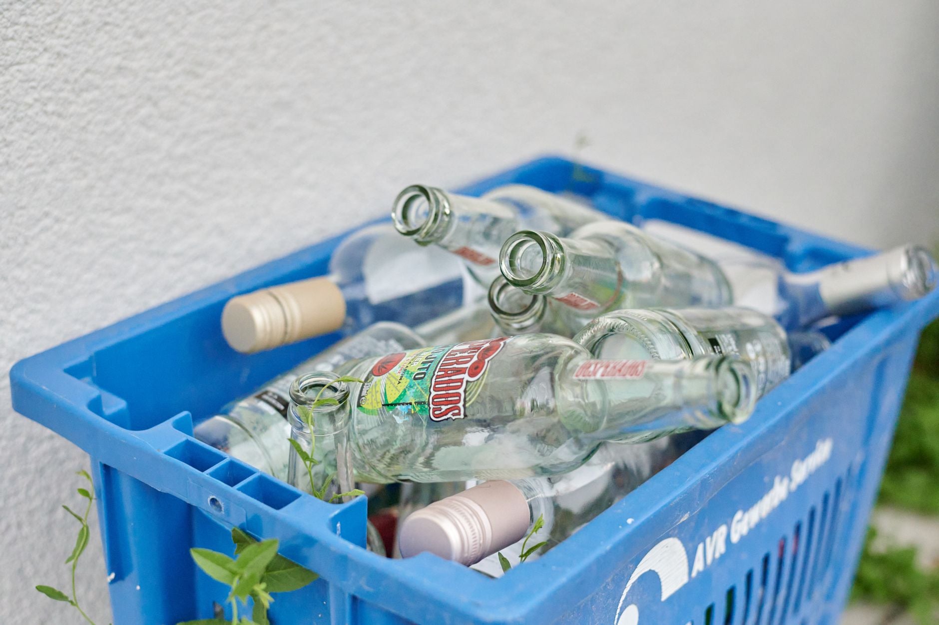 Blauwe krat gevuld met lege glazen flessen, klaar voor recycling. Duurzaam afvalbeheerconcept.