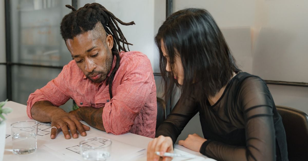 Two colleagues collaborate on design plans in a modern office setting. Focus on teamwork.