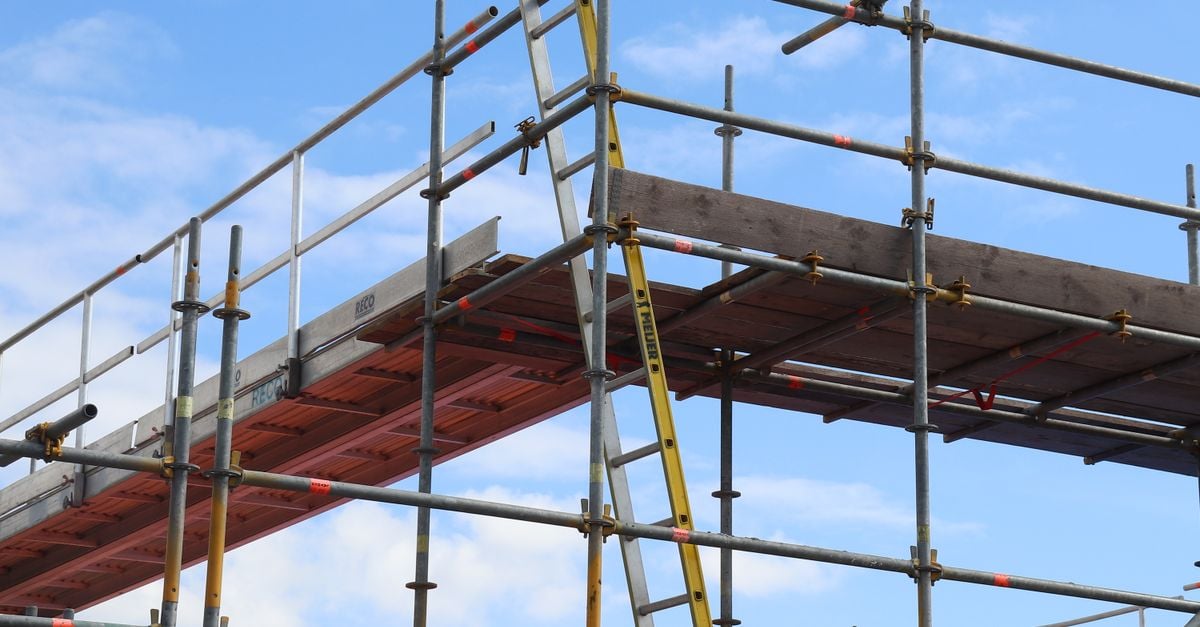 Gedetailleerde weergave van een steigerconstructie en een ladder op een bouwplaats tegen een helderblauwe lucht.