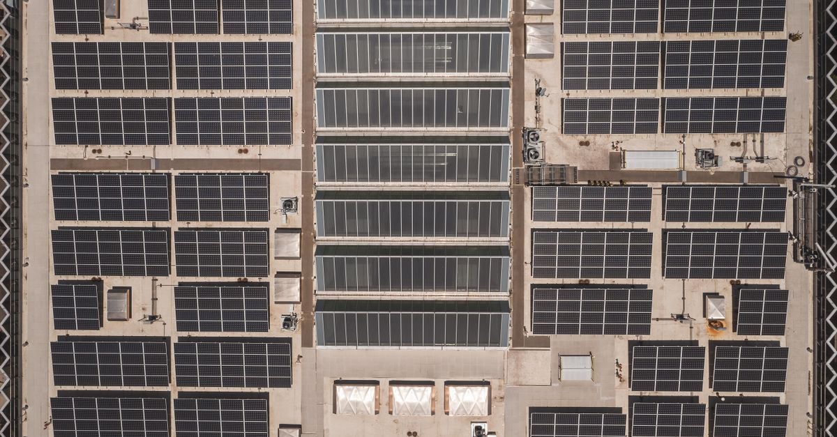 A high-angle drone shot capturing a grid of solar panels on a large industrial rooftop, showcasing renewable energy.
