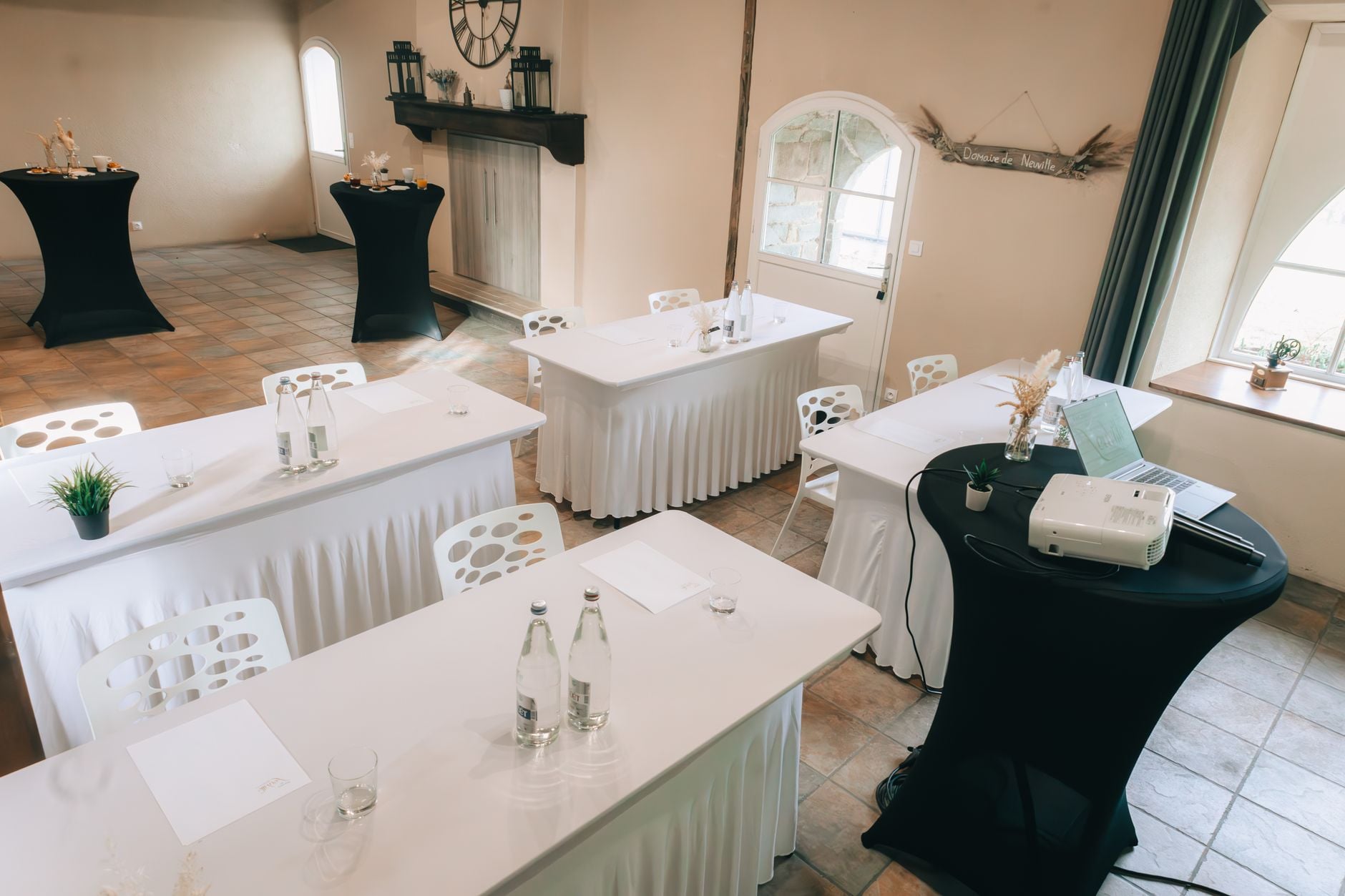 Ruime vergaderruimte met stijlvolle, met linnen bedekte tafels, stoelen en een projector, klaar voor presentaties.