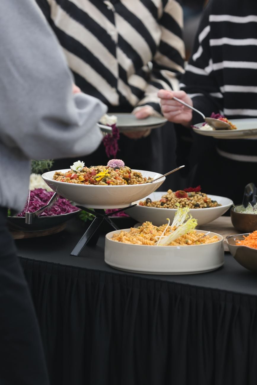 Een gevarieerd aanbod van kleurrijke gerechten op een buffet tijdens een bijeenkomst, met onder andere salades en granen.