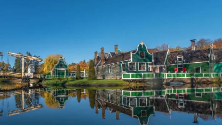 Historische groene houten huizen weerspiegeld in het water in het Nederlands Openluchtmuseum in Arnhem