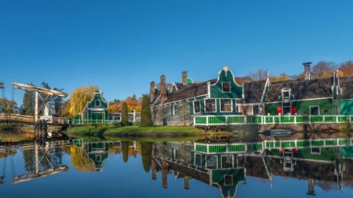 Historische groene houten huizen weerspiegeld in het water in het Nederlands Openluchtmuseum in Arnhem